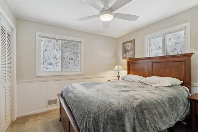 bedroom with ceiling fan, light colored carpet, and a closet