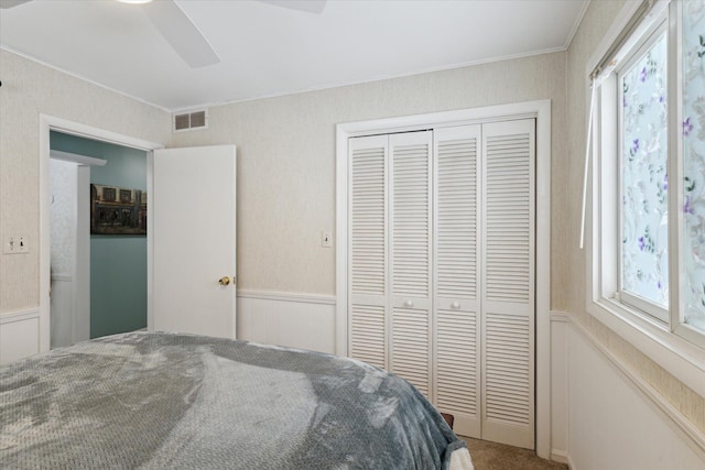 carpeted bedroom featuring ceiling fan, a closet, and ornamental molding