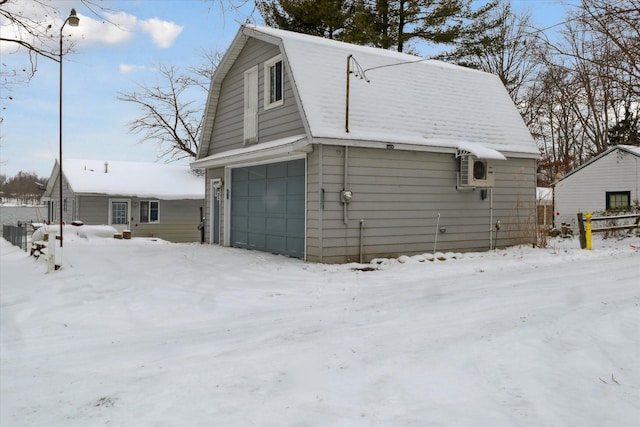 snow covered garage with ac unit