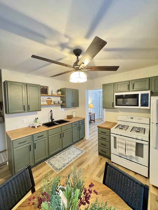 kitchen with white appliances, green cabinetry, wooden counters, and sink