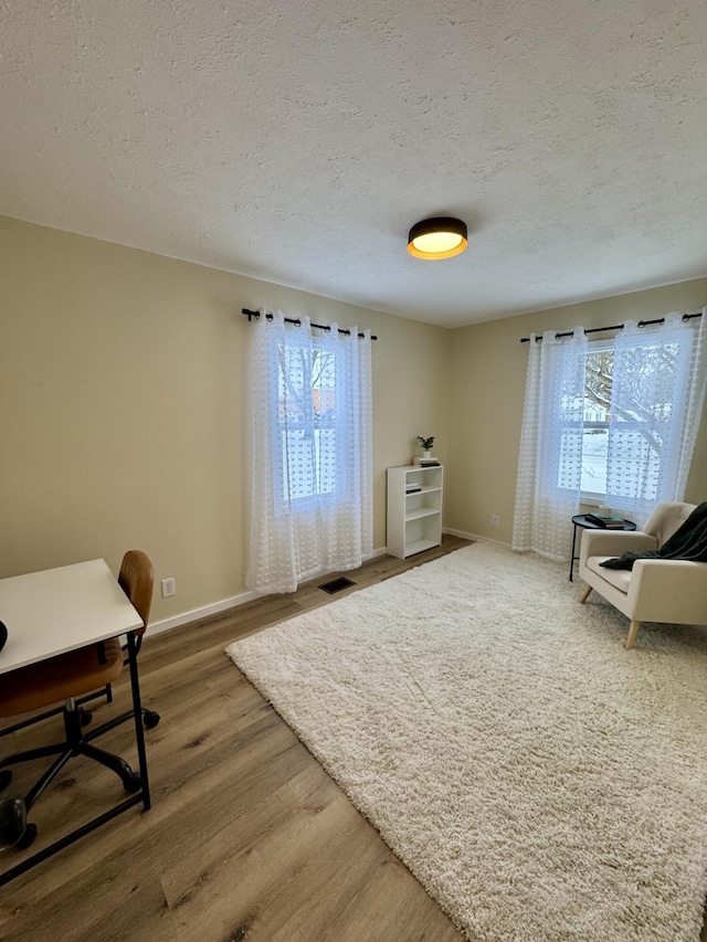 office space with a textured ceiling, a wealth of natural light, and hardwood / wood-style floors