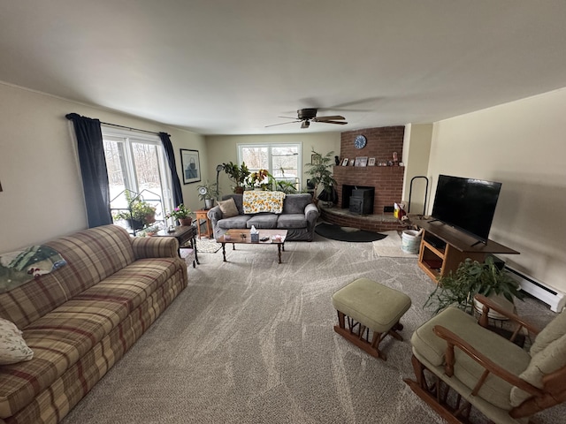 carpeted living room with ceiling fan, a baseboard heating unit, a wealth of natural light, and a brick fireplace