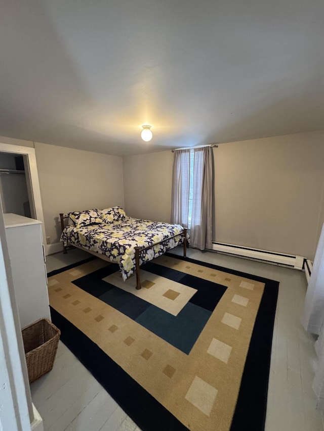 bedroom featuring hardwood / wood-style floors and a baseboard heating unit