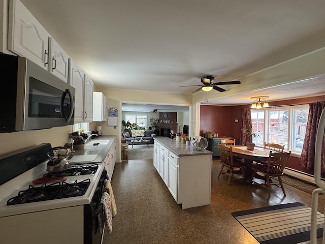 kitchen with gas range gas stove, ceiling fan with notable chandelier, sink, a center island, and white cabinetry