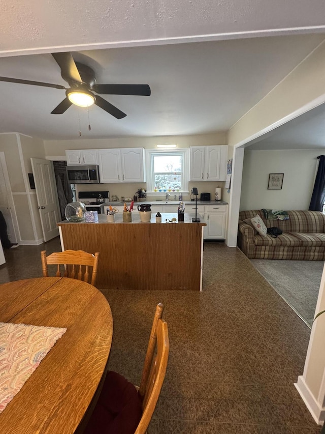 kitchen with white gas range, ceiling fan, white cabinetry, and sink