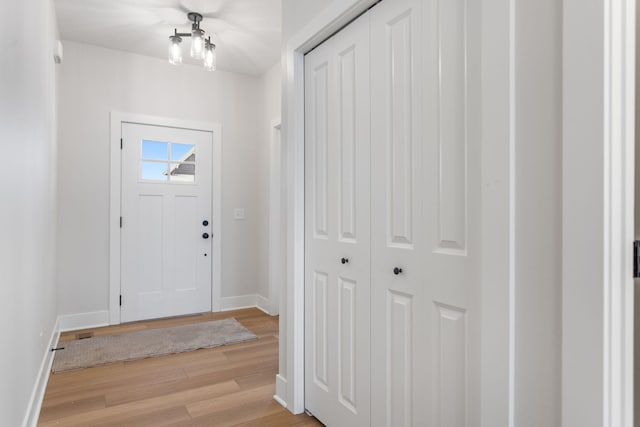 foyer with light hardwood / wood-style flooring and an inviting chandelier