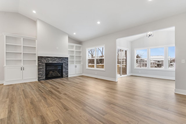 unfurnished living room with plenty of natural light, a stone fireplace, and lofted ceiling