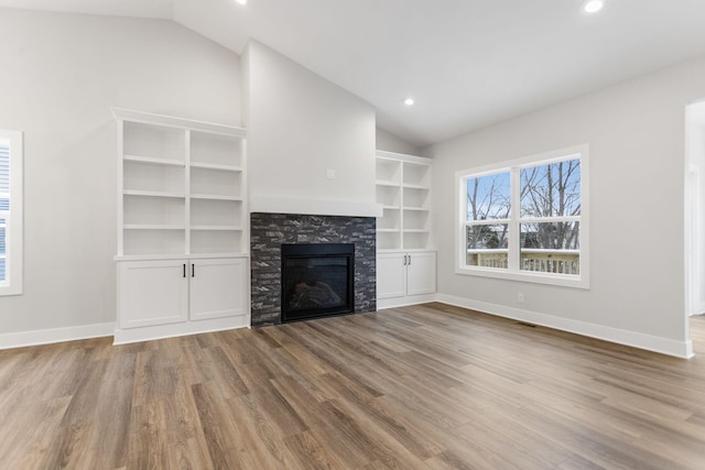 unfurnished living room with a fireplace, light hardwood / wood-style floors, and lofted ceiling