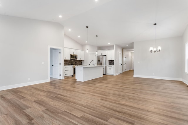 unfurnished living room with high vaulted ceiling, light hardwood / wood-style flooring, an inviting chandelier, and sink