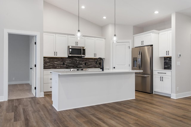 kitchen with appliances with stainless steel finishes, white cabinetry, pendant lighting, and an island with sink