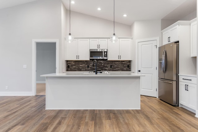 kitchen featuring white cabinetry, hanging light fixtures, an island with sink, and stainless steel appliances