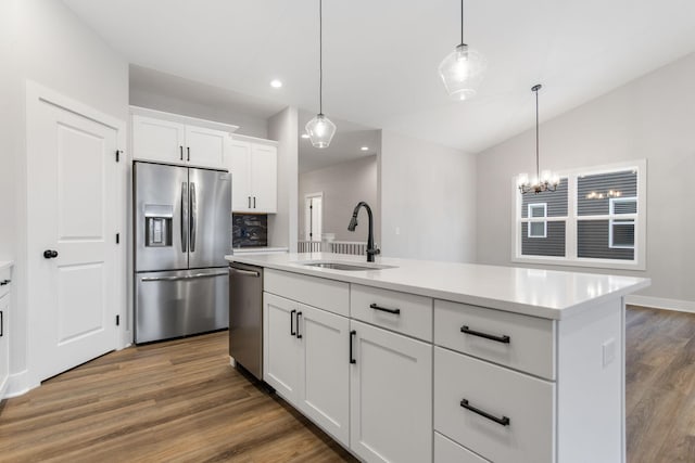 kitchen with stainless steel appliances, sink, a center island with sink, white cabinets, and hanging light fixtures