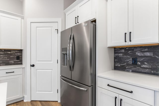 kitchen featuring stainless steel fridge, light wood-type flooring, white cabinetry, and tasteful backsplash