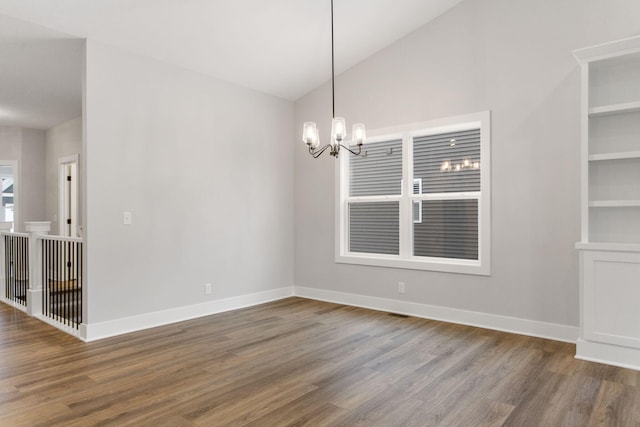 spare room with a notable chandelier, dark hardwood / wood-style floors, and lofted ceiling