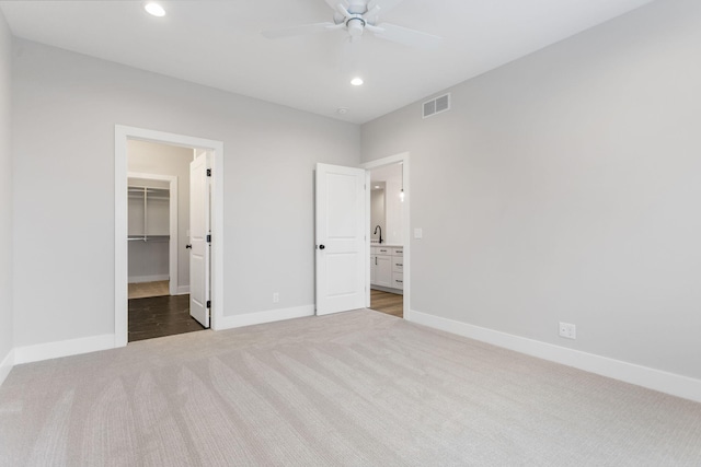 unfurnished bedroom with carpet flooring, a closet, a spacious closet, and ceiling fan