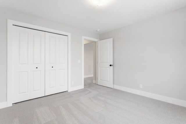 unfurnished bedroom with light carpet and a closet