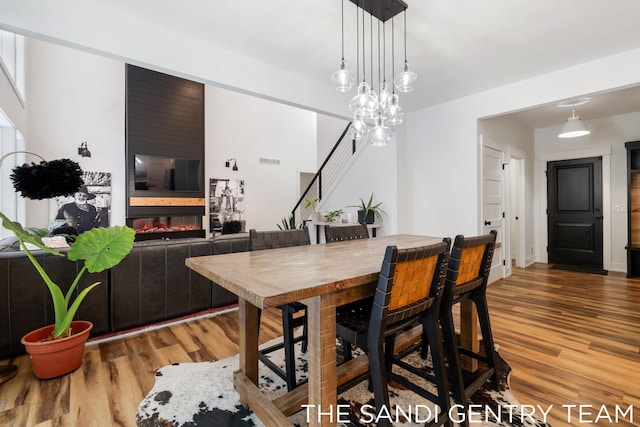 dining space featuring a chandelier, hardwood / wood-style floors, and a large fireplace