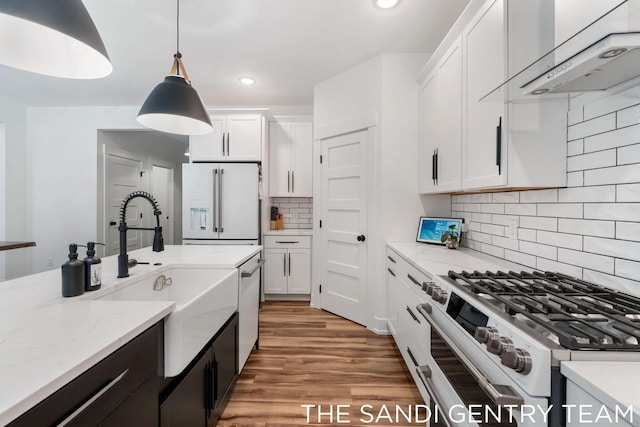 16500 Haven Woods Ct, West Olive, MI 49460 - kitchen featuring high end stainless steel range oven, white refrigerator with ice dispenser, extractor fan, white cabinets, and hanging light fixtures