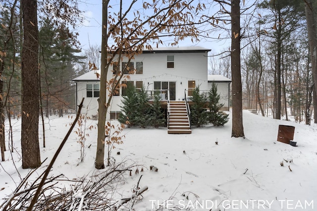 snow covered house with a wooden deck