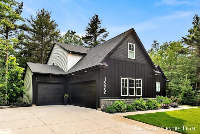 16500 Haven Woods Ct, West Olive, MI 49460 - view of front of property with board and batten siding, an attached garage, concrete driveway, and a shingled roof