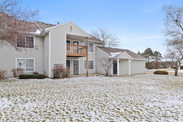 snow covered rear of property featuring a balcony