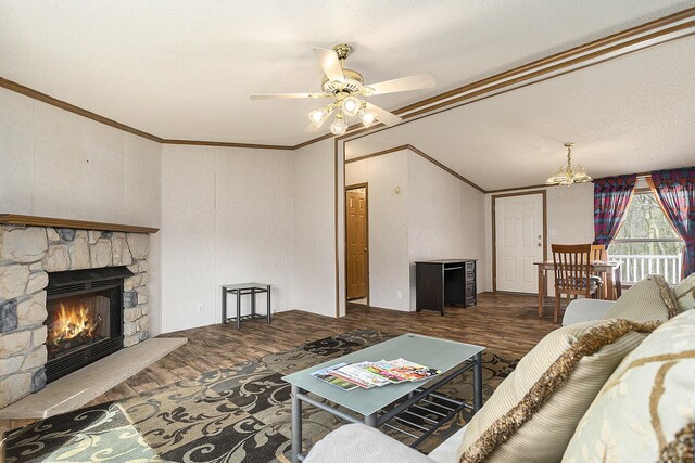 living room featuring ceiling fan, a stone fireplace, hardwood / wood-style floors, vaulted ceiling, and ornamental molding