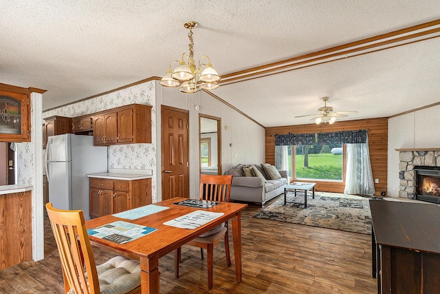 dining space featuring a textured ceiling, a healthy amount of sunlight, dark wood-type flooring, and ceiling fan with notable chandelier