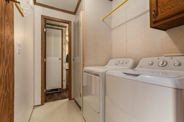 laundry area featuring washer and dryer, cabinets, a textured ceiling, and ornamental molding