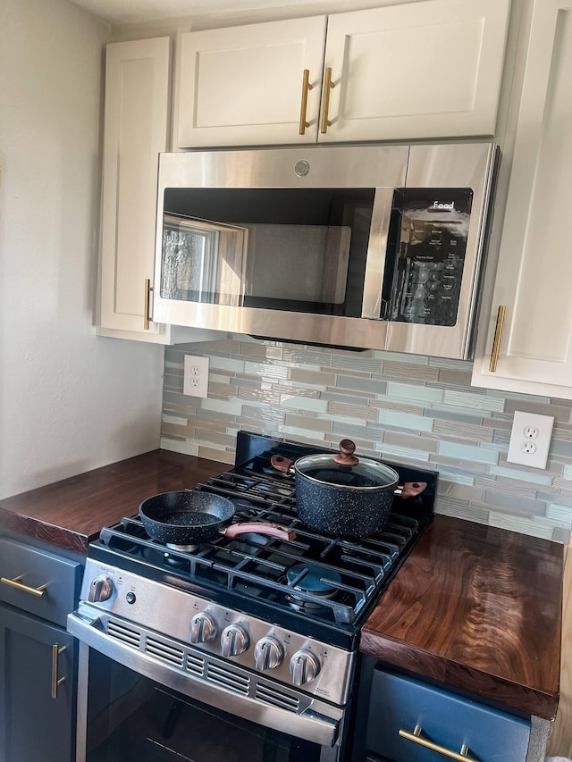 kitchen featuring white cabinets, blue cabinetry, appliances with stainless steel finishes, and tasteful backsplash