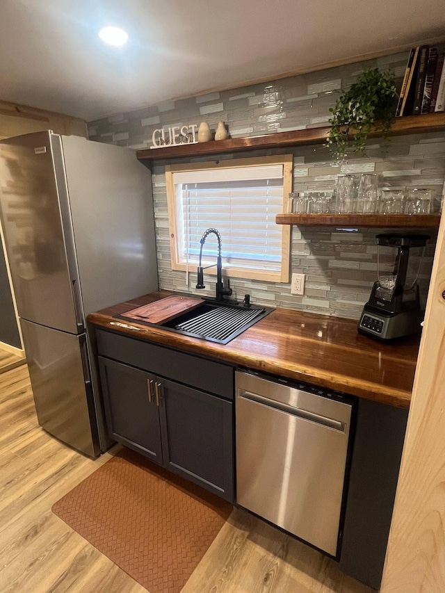 kitchen featuring butcher block countertops, sink, stainless steel appliances, and light hardwood / wood-style flooring