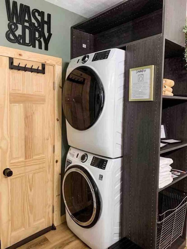 laundry area featuring hardwood / wood-style floors and stacked washing maching and dryer