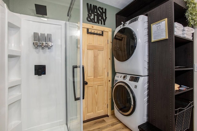 laundry room featuring stacked washer and clothes dryer and light wood-type flooring