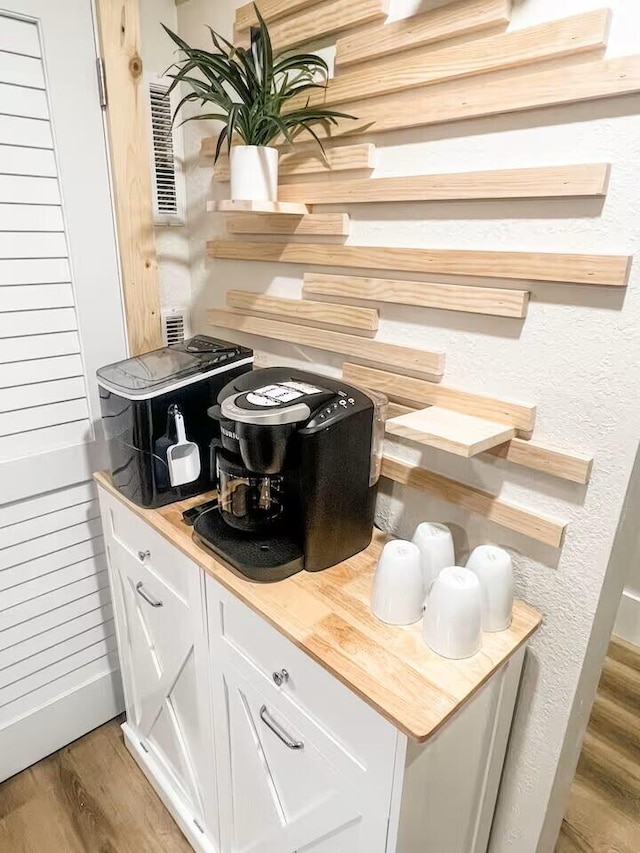 interior space with butcher block countertops, white cabinets, and hardwood / wood-style flooring