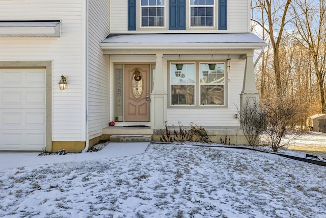 snow covered property entrance featuring a garage