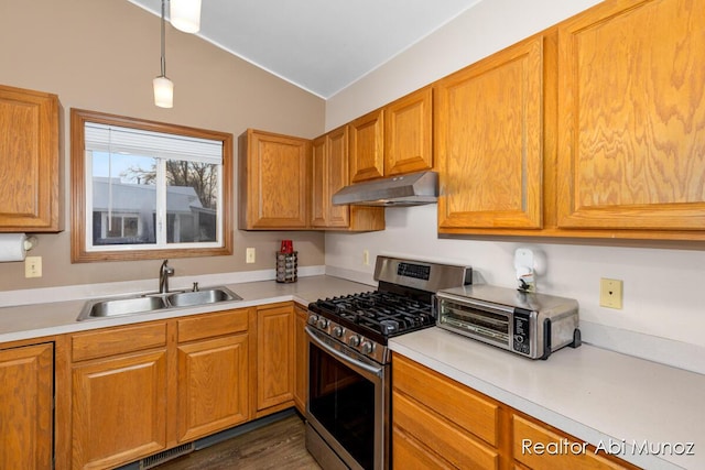 kitchen featuring stainless steel gas stove, sink, dark hardwood / wood-style flooring, lofted ceiling, and decorative light fixtures