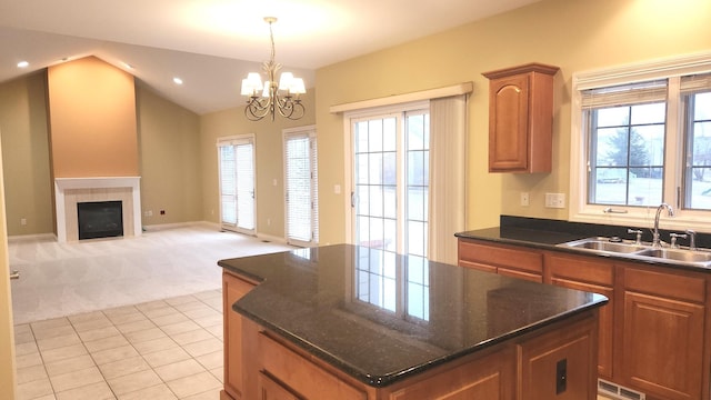 kitchen featuring light carpet, sink, an inviting chandelier, a fireplace, and a kitchen island