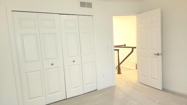 unfurnished bedroom with light colored carpet and a closet