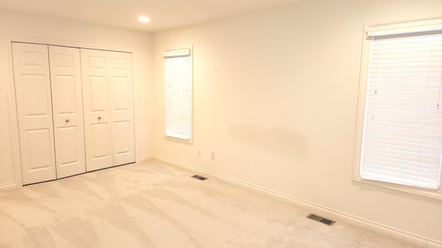 unfurnished bedroom with light carpet and a closet