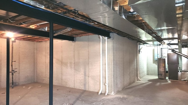 basement with gas water heater, heating unit, and brick wall