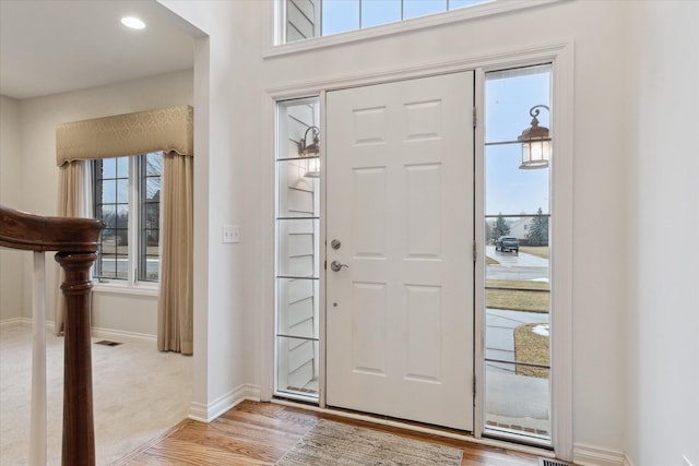 foyer entrance with light wood-type flooring, visible vents, and baseboards