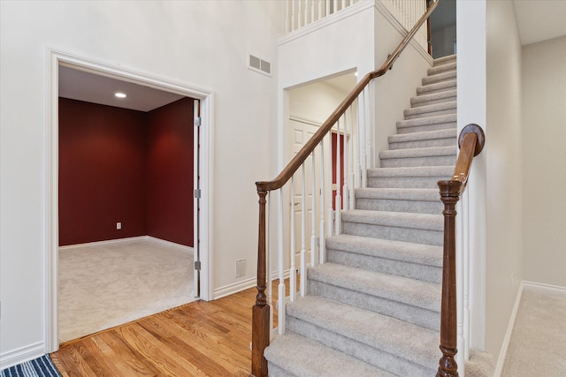 stairway with carpet flooring, visible vents, baseboards, and wood finished floors