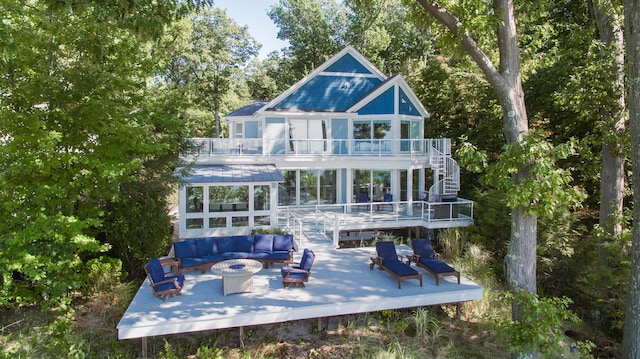 back of property featuring stairs, a deck, an outdoor living space with a fire pit, and a balcony