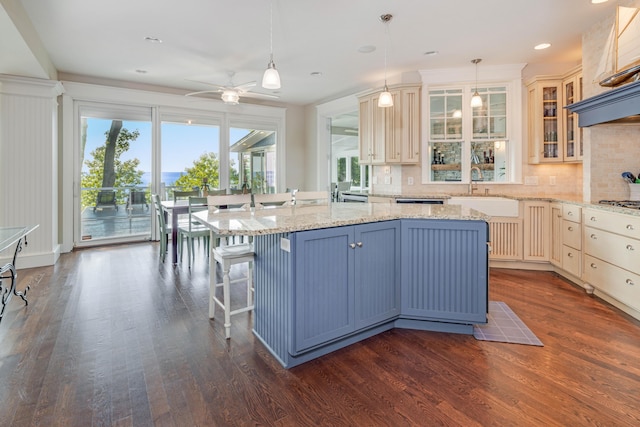 kitchen featuring glass insert cabinets, decorative light fixtures, a sink, and an island with sink