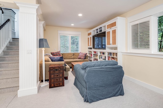 living area with light carpet, decorative columns, baseboards, stairway, and recessed lighting