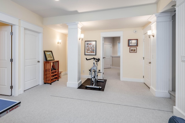 exercise area with light carpet, decorative columns, and baseboards