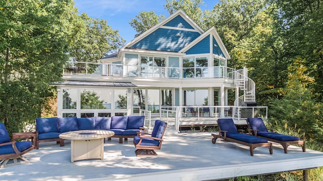 rear view of property featuring an outdoor living space with a fire pit, a balcony, a wooden deck, and stairs