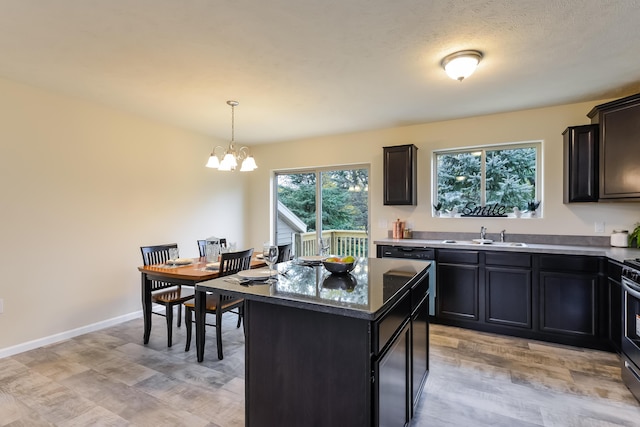 kitchen featuring sink, stainless steel stove, hanging light fixtures, a notable chandelier, and a kitchen island