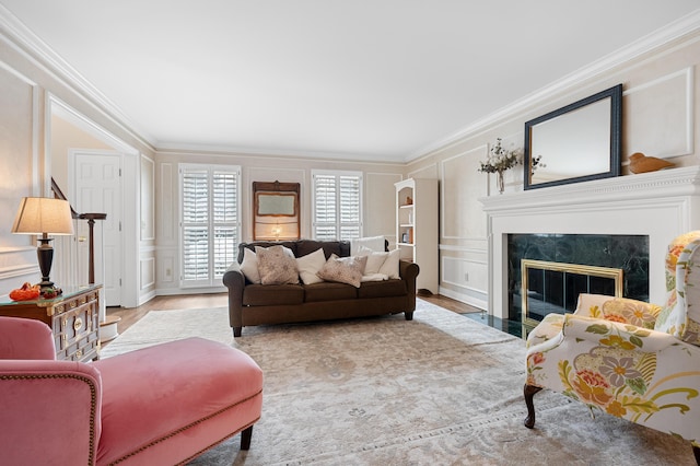 living area featuring ornamental molding, a fireplace, light wood-style flooring, and a decorative wall