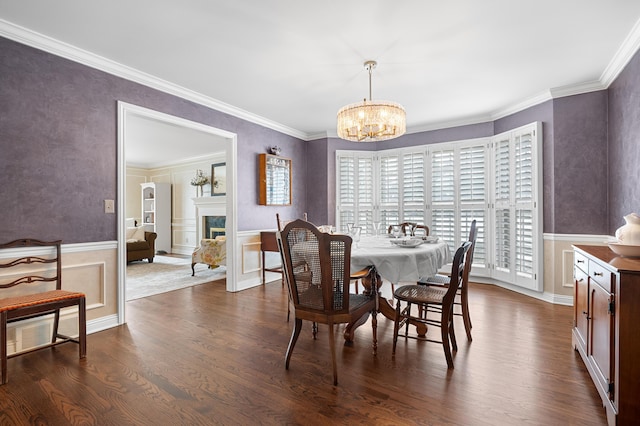 dining area with dark wood-style floors, wainscoting, a fireplace, and a chandelier