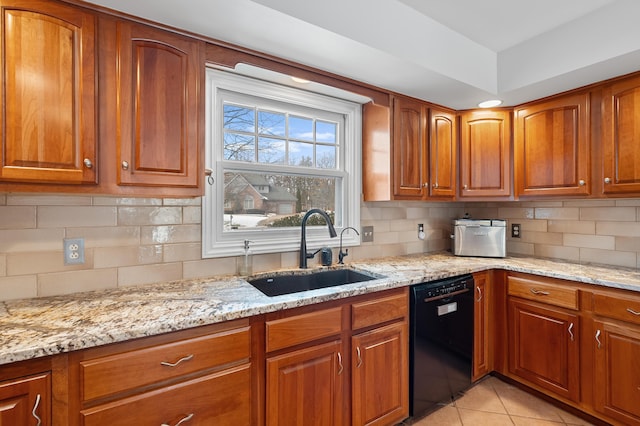 kitchen with a sink, light stone countertops, brown cabinetry, and dishwasher
